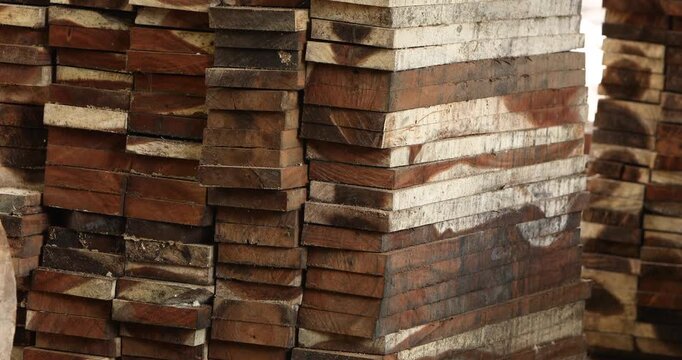 Stacked wooden lumber planks at a timber yard, showing raw wood materials for construction, woodworking and furniture production, with natural grain and rustic texture.