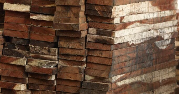 Stacked wooden lumber planks at a timber yard, showing raw wood materials for construction, woodworking and furniture production, with natural grain and rustic texture.