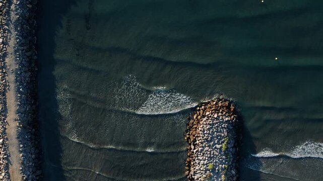 Top Down Aerial View of Waves Crashing on Rock Breakwater