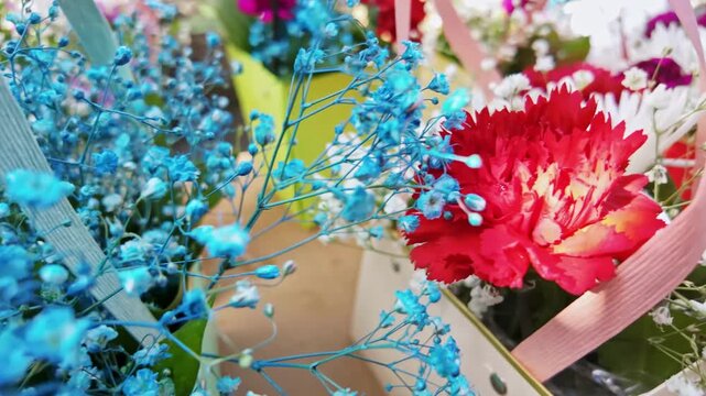Dyed blue flowers cluster near red carnations in a festive bouquet.