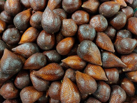 A dense pile of fresh snake fruit (salak pondoh) showcasing their distinctive brown, scaly, teardrop-shaped skin in close-up detail.