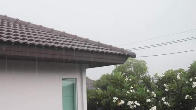 Heavy rain falling on dark roof tiles of modern house during stormy weather