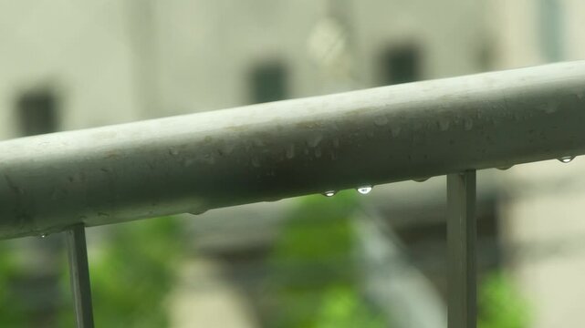 雨の中で濡れるベランダの手すり、滴る水滴と青々とした背景