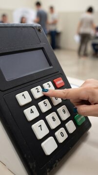 voter pressing number button on electronic voting machine key pad during official democratic election process in polling station