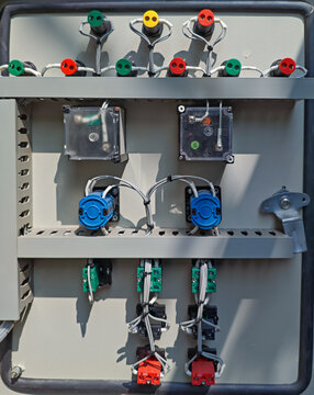 Detailed close-up of an open industrial electrical control panel with various colorful buttons, switches, wires, and internal components arranged neatly.