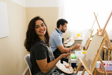 Happy woman learning to paint during adult art class in a workshop, expressing creativity and finding a new hobby © AntonioDiaz