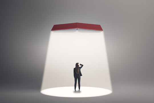 Businesswoman Seen From Behind Under a Spotlight and Open Book, Symbolizing Education, Learning, Study, Ambition, Career Growth, and New Opportunities.
