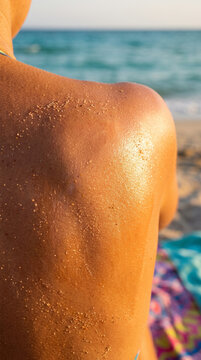 Suntanned and Sandy Back of Woman on Beach with Glistening Sea Salt and Sunscreen Glow