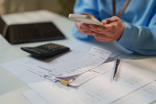 Business specialist cross-referencing printed store receipts and audit paperwork managing mobile expense software, automated accounts payable, OCR document processing, cloud-based bookkeeping solution