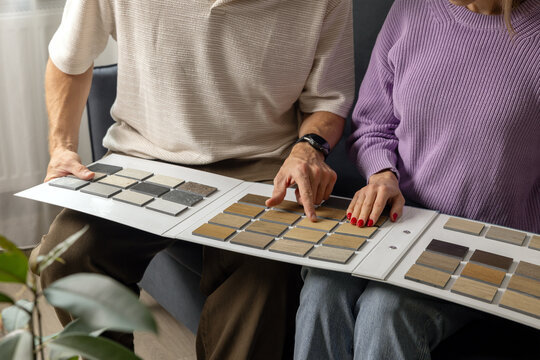 Couple choosing flooring and furniture materials from wood samples for home renovation. Interior design
