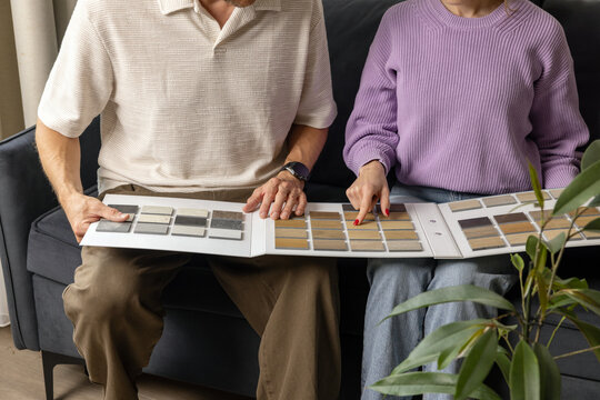 Couple choosing flooring and furniture materials from wood samples for home renovation. Interior design
