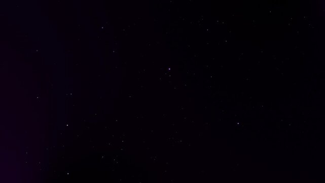 Glittering purple particles floating and shimmering on dark background