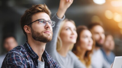 Obraz premium Curiosity in the Classroom: A young student with glasses raises his hand, eager to ask a question in a sunlit lecture hall, surrounded by classmates engaged in learning.