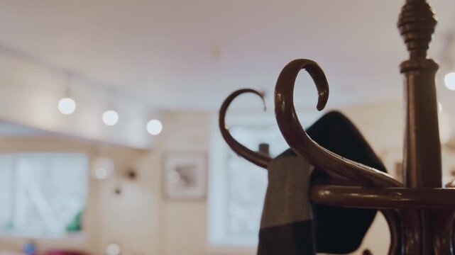 Close up of person hand holding and examining black fabric items on wooden hangers in indoor setting with soft lighting. scene shows interaction between hands textiles and metal hooks