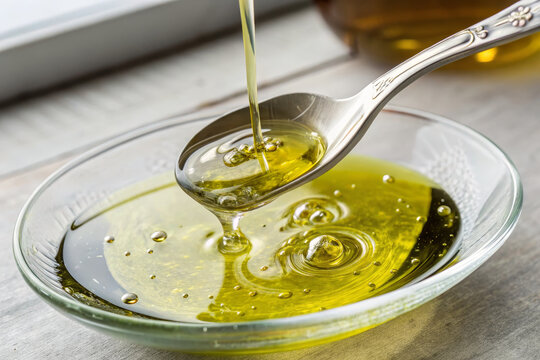 Olive oil swirl clear glass spoon golden liquid healthy ingredient Mediterranean cuisine closeup natural organic kitchen fresh