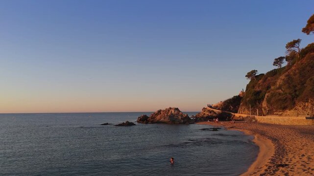 Aerial view taken from a drone of the coast of Lloret de Mar, Costa Brava, Spain, early in the morning at sunrise - the sea, beach and coastal cliffs of the city bay