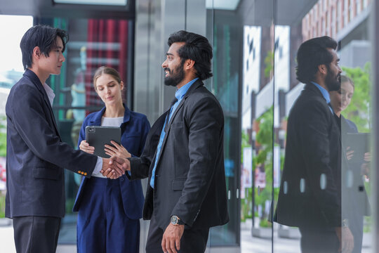 Three young business professionals wearing conference badges head through the corporate campus in step on the open terrace of a modern corporate campus in the city centre