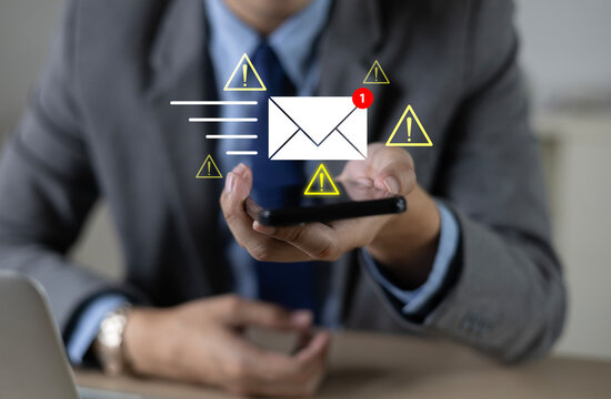 A hand holding a smartphone with an envelope icon and a warning icon displays email and digital communication notifications, including online inbox message notifications.