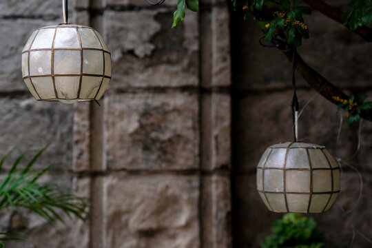 Traditional Capiz Shell Globe Lanterns Hanging Outdoors Against Rustic Old Stone Wall
