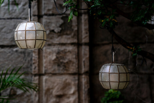 Traditional Capiz Shell Globe Lanterns Hanging Outdoors Against Rustic Old Stone Wall