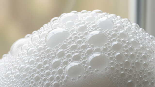Macro closeup of dense white foam bubbles forming layered organic texture with glossy spheres delicate reflections translucent edges clustered surface abstract pattern soft illumination creamy backgro