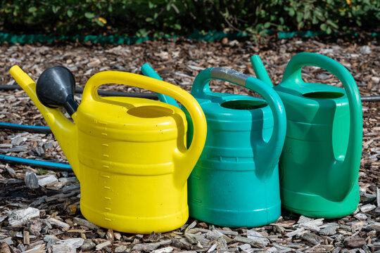 Threesome of colorful water cans in garden