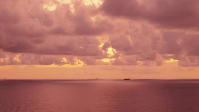 Distant Cargo Ship on Ocean Horizon Under Dramatic Pink Dusk Clouds