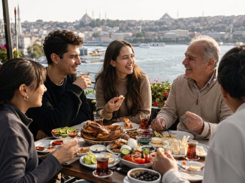 Reisegruppe genie&szlig;t ein traditionelles t&uuml;rkisches Fr&uuml;hst&uuml;ck auf einer sonnigen Terrasse am Bosporus in Istanbul &ndash; authentische Kulinarik, Gastfreundschaft und lokaler Tourismus.