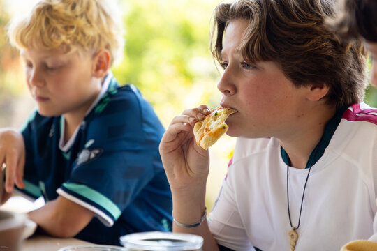 teenage boy eating lunch with his friends at outdoor patio