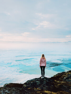 Woman standing alone overlooking frozen lake in Norway quiet winter nature, solo travel adventure outdoor lifestyle solitude contemplation mindfulness freedom Scandinavian nature exploration