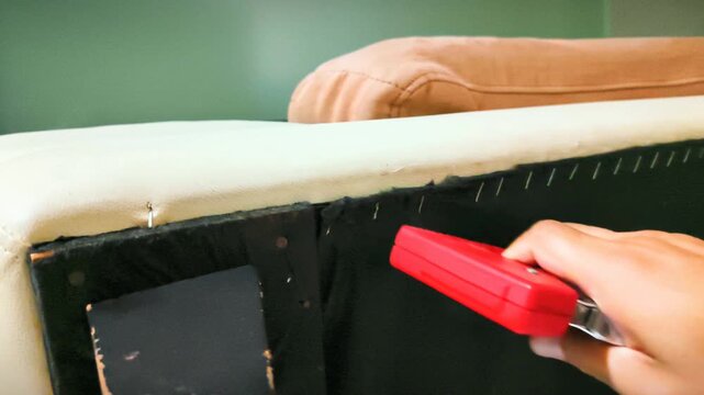 Man Repairing Sofa Dust Cover Fabric Underneath Using Staple Gun
