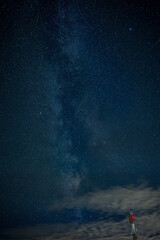 Fototapeta premium Milky Way stretching across a star-filled August night sky above a telecommunications tower and drifting clouds, combining astronomy, wireless technology and modern infrastructure.
