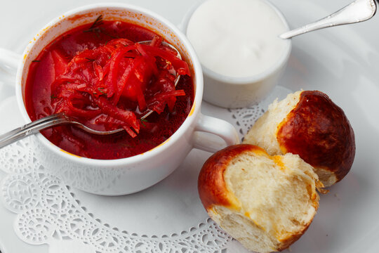 Traditional Ukrainian borscht with beetroot, shredded vegetables, sour cream and fresh bread rolls