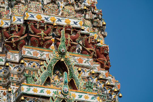 Demon statues and bronze bells decorating Wat Arun Prang tower