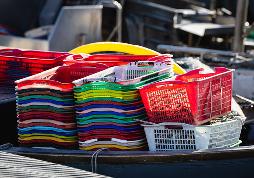 Stacking colorful plastic fishing baskets in Goro port