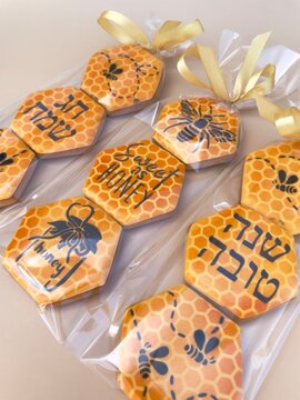Rosh Hashanah honey cookies decorated with Shana Tova and Chag Sameach greetings, honeycomb patterns, bee motifs and golden ribbons