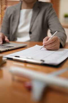 Asian Businesswoman reviewing logistics documents beside a laptop with airplane model in foreground, representing air freight, cargo shipping, transportation planning and global trade operations.