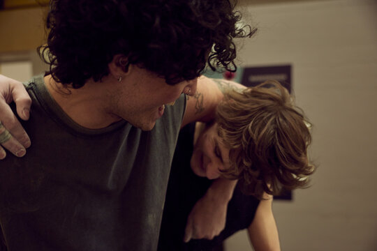 Young diverse friends laughing and embracing as one gives the other a playful piggyback hug indoors
