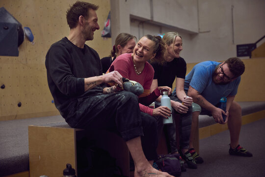 Friends laughing and resting together at an indoor bouldering gym after a climbing session