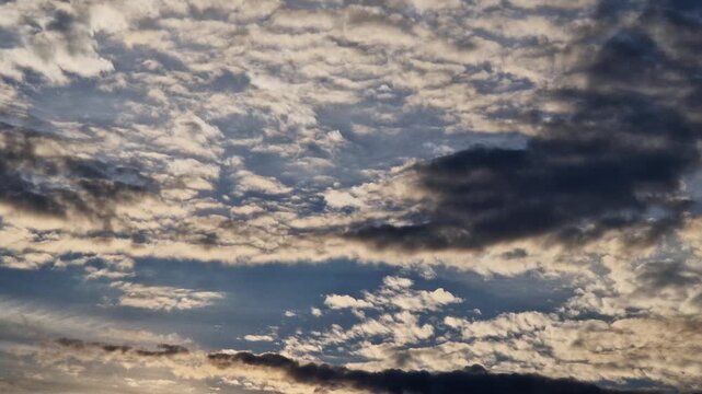 Cloudy sky at sunset. A combination of light stratocumulus and dense dark clouds. Pre-storm evening landscape with contrasting clouds. Pre-storm nature and changeable weather