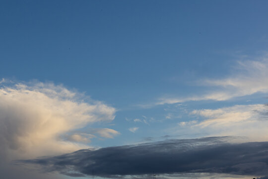 Spectacular Cloud Formation Against Deep Blue Sky Above a Distant Horizon. Beautiful natural cloudscape with large sculptural white and gray cloud formations rising above a distant dark horizon. 