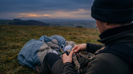 Fototapeta premium Paraglider preparing equipment on grassy hill at dusk