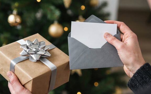 Person holding a gift box and a blank card in an envelope