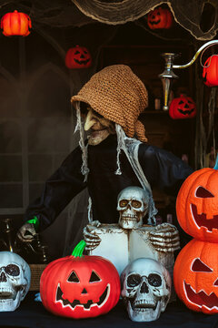 Halloween witch prop surrounded by carved jack o lantern pumpkins and skulls decoration. creepy Halloween witch prop, Halloween party decor, spooky event marketing, and seasonal holiday background.