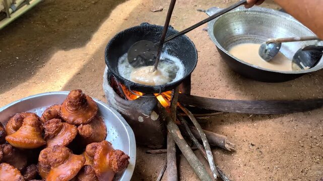 Close-up 4K video showing the traditional technique of forming the signature top peak (Konda) of a Sri Lankan Kavum. The cook uses a wooden skewer in one hand while