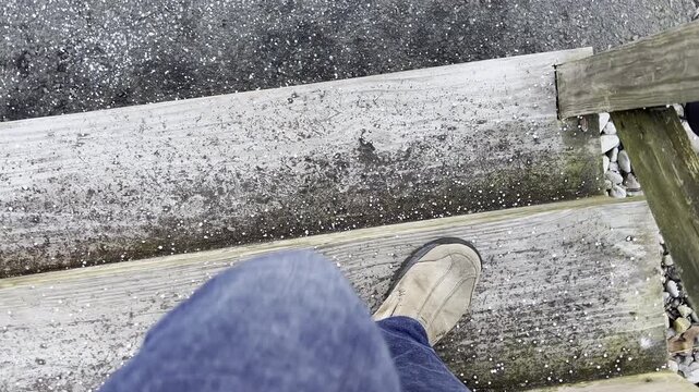 woman carefully stepping down frozen salted wooden stairs in winter