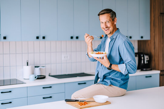 Smiling Man Eating Healthy Breakfast in Modern Kitchen &mdash; Casual Home Lifestyle and Morning Routine