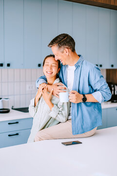 Happy Couple Embracing in Modern Kitchen Sharing Coffee and Morning Affection at Home