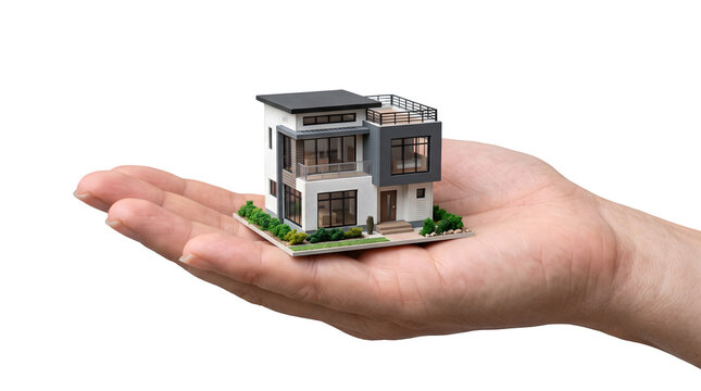 A small scale architectural model of a modern luxury house held in a human hand