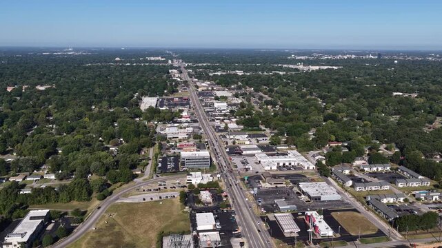 Aerial of suburban commercial strip and intersection in Springfield Missouri with dense forest canopy surrounding the major thoroughfare